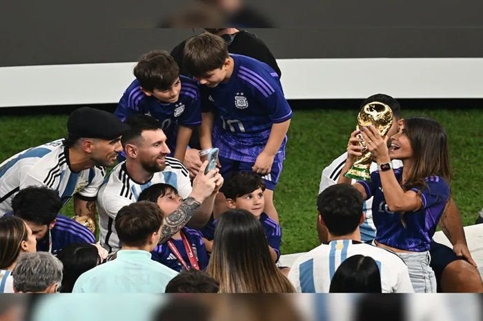 Lionel Messi saat memotret isterinya yang memegang trofi Piala Dunia 2022