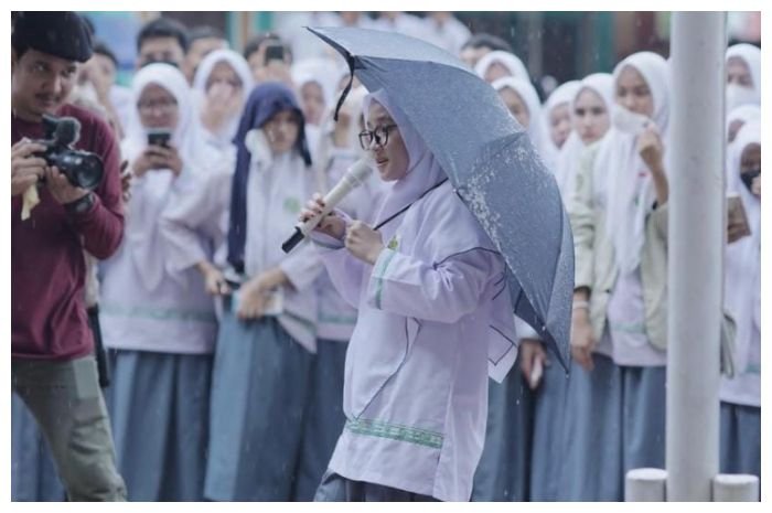 Nissa Sabyan bak menjadi ojek payung saat pentas di sebuah sekolah.