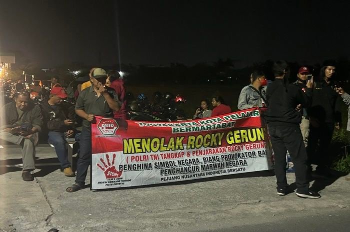Massa menghadang dan membawa spanduk yang mengecam Rocky Gerung