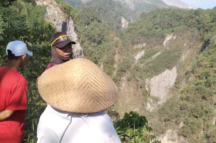 Warga melihat tebing Sungai Trising yang longsor